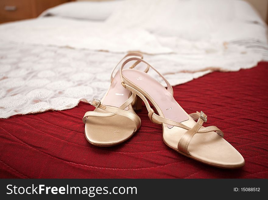 Wedding golden shoes and white dress laying on the red cover. Wedding golden shoes and white dress laying on the red cover.