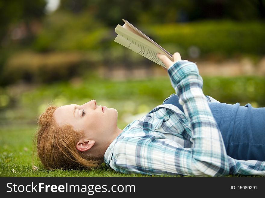 Young woman sitting outside reading. Young woman sitting outside reading