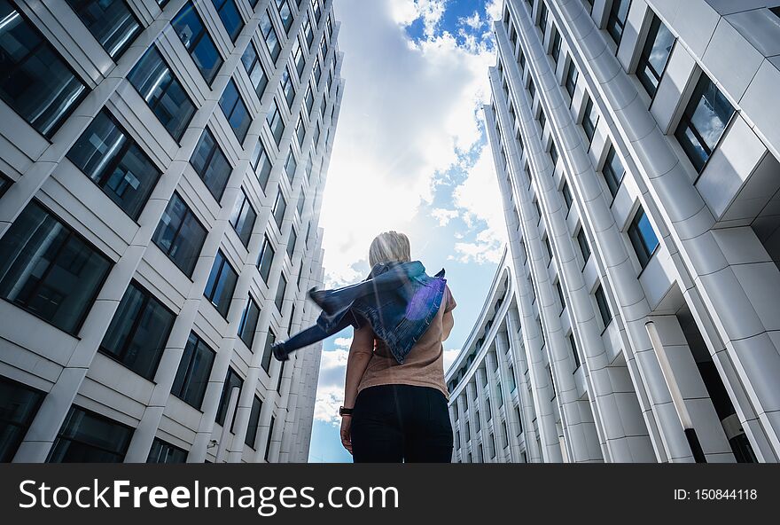 Back View. The Girl Walks Between The Houses With Her Back To The Camera.