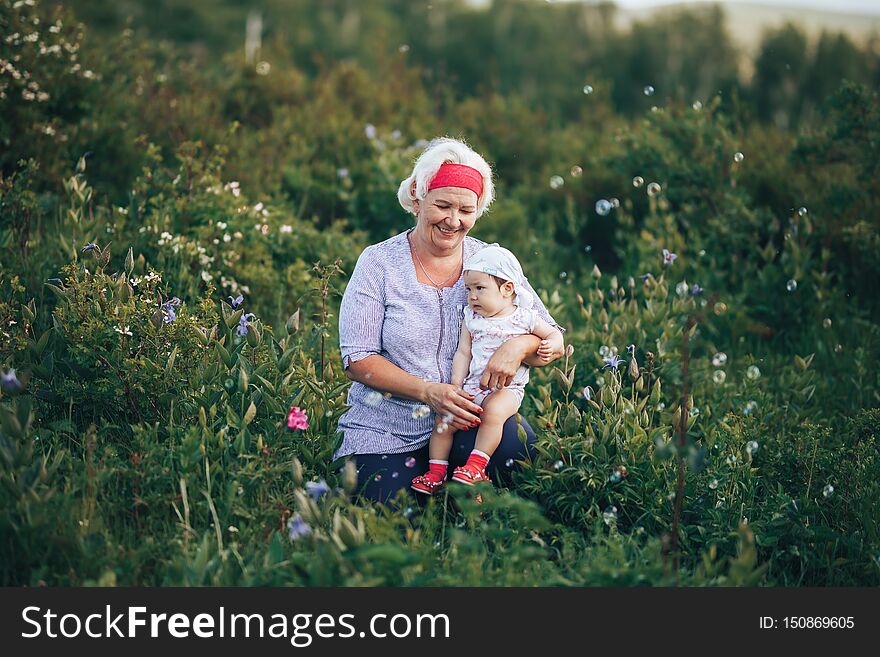 Grandmother Hugging Granddaughter In Nature In Sunny Summer Day