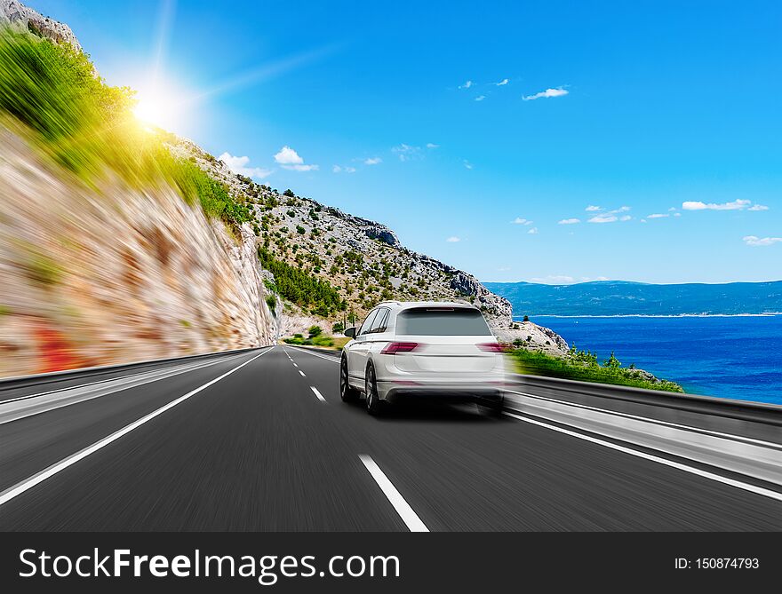 White car rushes along the road to the sea. Motion blur effect.