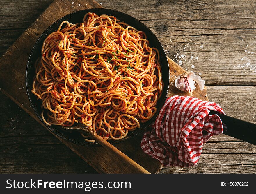 Tasty italian classic spaghetti with tomato sauce cooked in pan. Old wooden table background. Rustical. View from above. Cooking process. Tasty italian classic spaghetti with tomato sauce cooked in pan. Old wooden table background. Rustical. View from above. Cooking process
