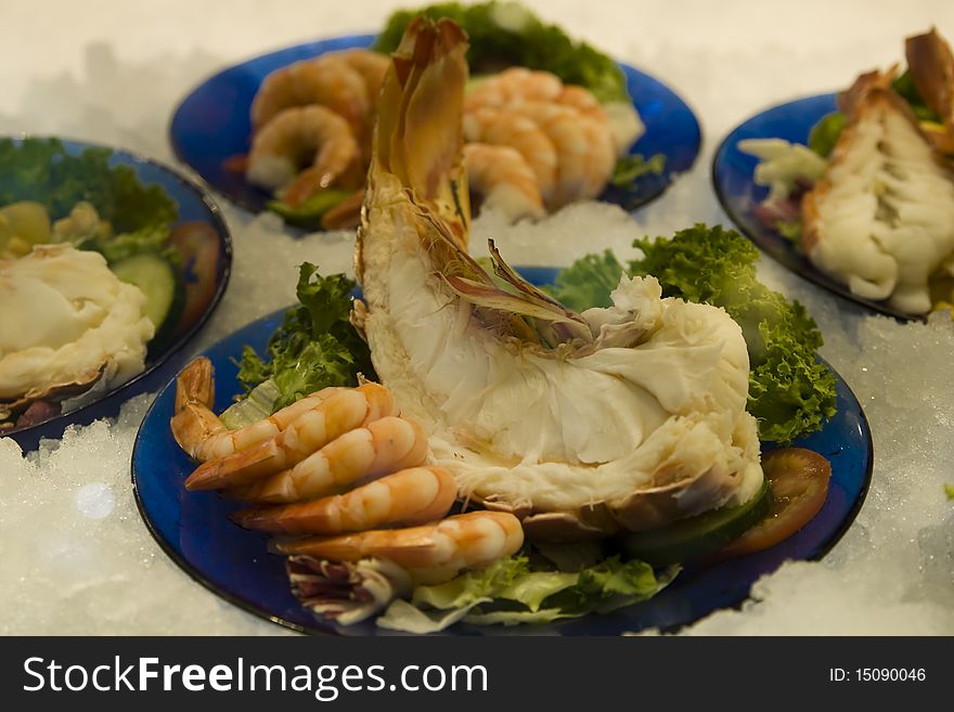 Lot of fresh delicious shrimps with decorated green salad in a fish restaurant. Lot of fresh delicious shrimps with decorated green salad in a fish restaurant.