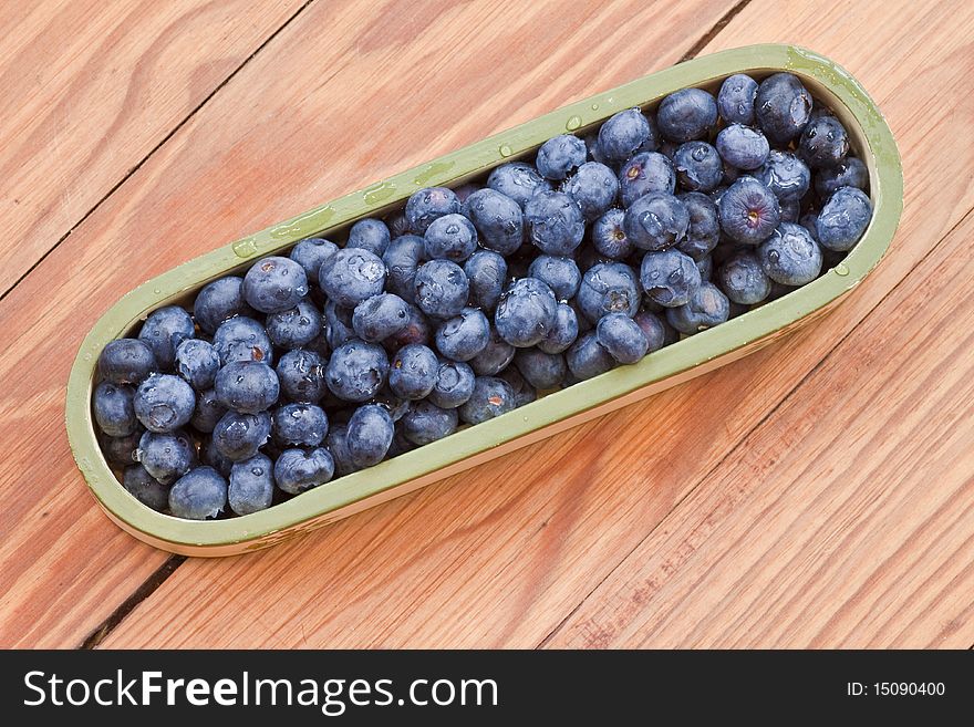 Blueberries in a container on a wooden table. Blueberries in a container on a wooden table