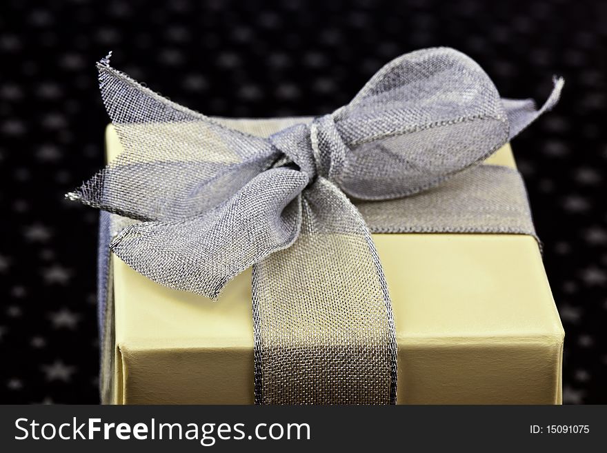 Gift box wrapped with silver ribbon on a silver stars and black background. Gift box wrapped with silver ribbon on a silver stars and black background