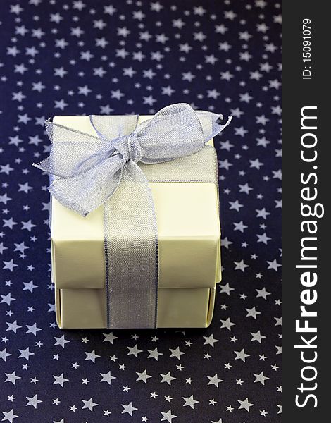 Gift box wrapped with silver ribbon on a silver stars and black background. Gift box wrapped with silver ribbon on a silver stars and black background