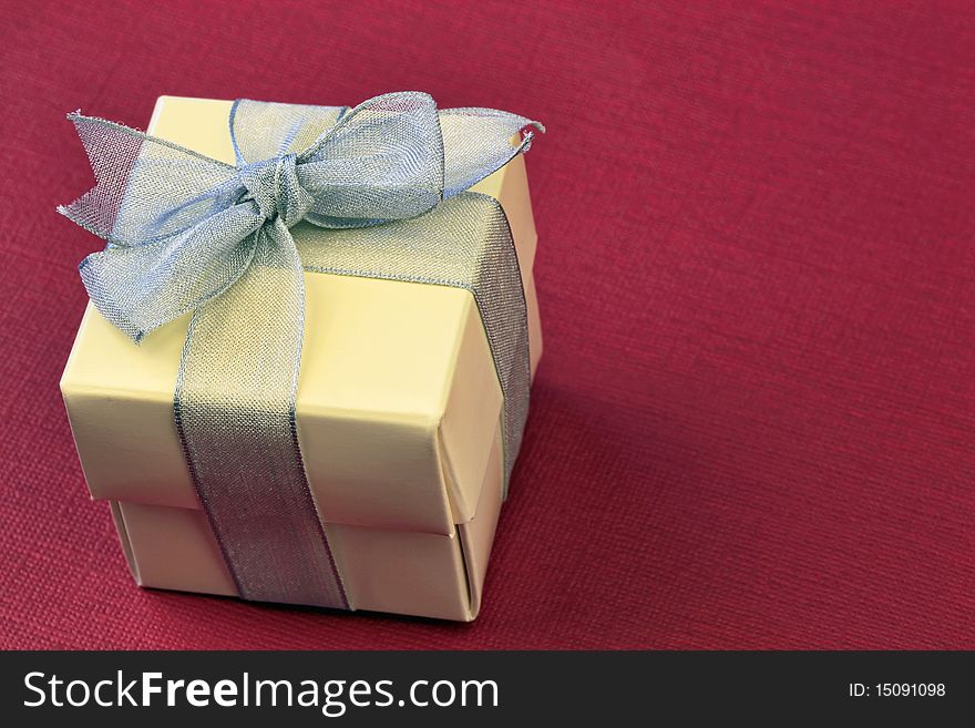 Gift box with silver ribbon over red background. Gift box with silver ribbon over red background