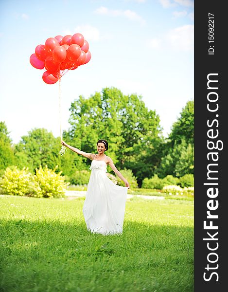 Bride in white dress with balloons on green field. Bride in white dress with balloons on green field