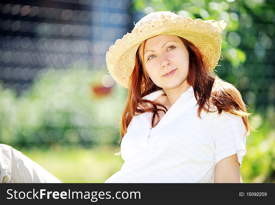 Young woman in straw hat  sitting on green grass