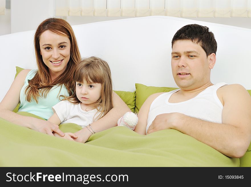 Happy young family at home relaxing in bed. Happy young family at home relaxing in bed