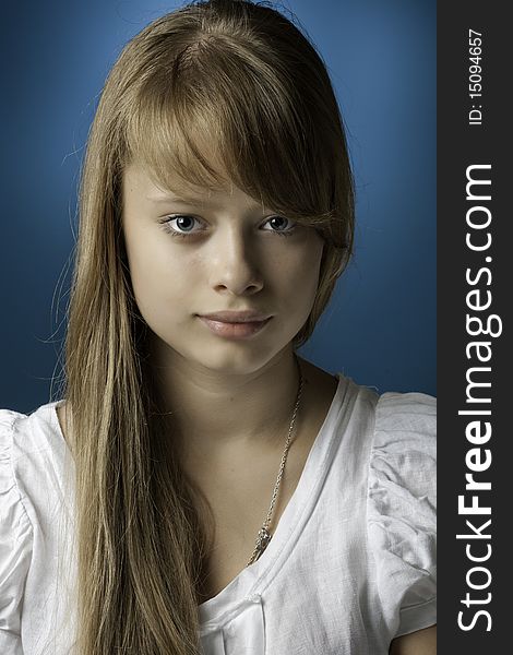 Portrait of the girl-teenager with a long blond hair on a dark blue background