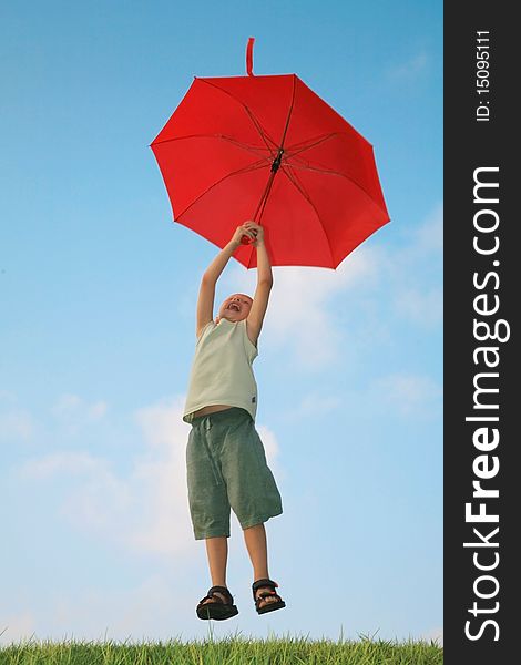 White boy flying on a red umbrella and laughing against the blue summer sky. White boy flying on a red umbrella and laughing against the blue summer sky