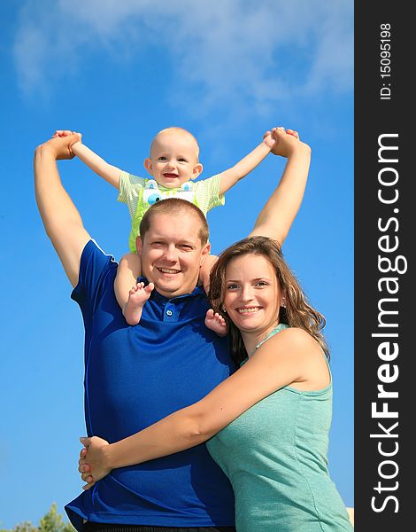 Mom dad and son happily smiling in the bright blue summer sky background. Mom dad and son happily smiling in the bright blue summer sky background