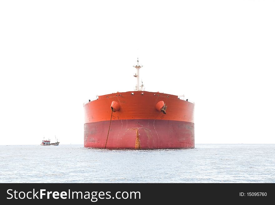 High key photo of orange oil tanker at anchor with the sky completely white. Small fishing vessel to the left. High key photo of orange oil tanker at anchor with the sky completely white. Small fishing vessel to the left.