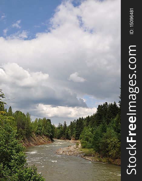 Mountain small river with woody coast in a summer landscape under clouds. Mountain small river with woody coast in a summer landscape under clouds