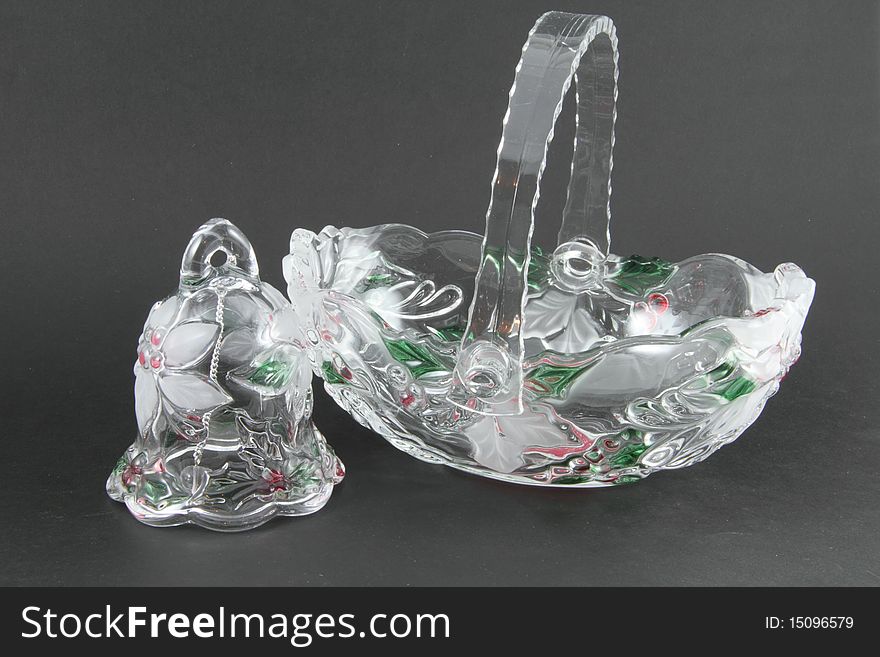 A crystal basket and bell holiday decorations on a grey background.