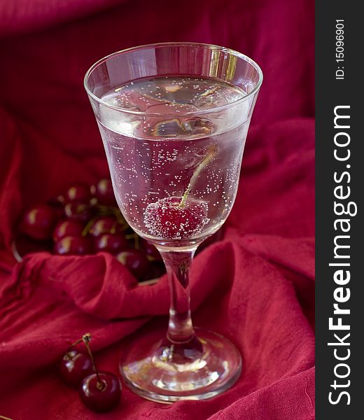 Glass of water with juicy cherry and ice