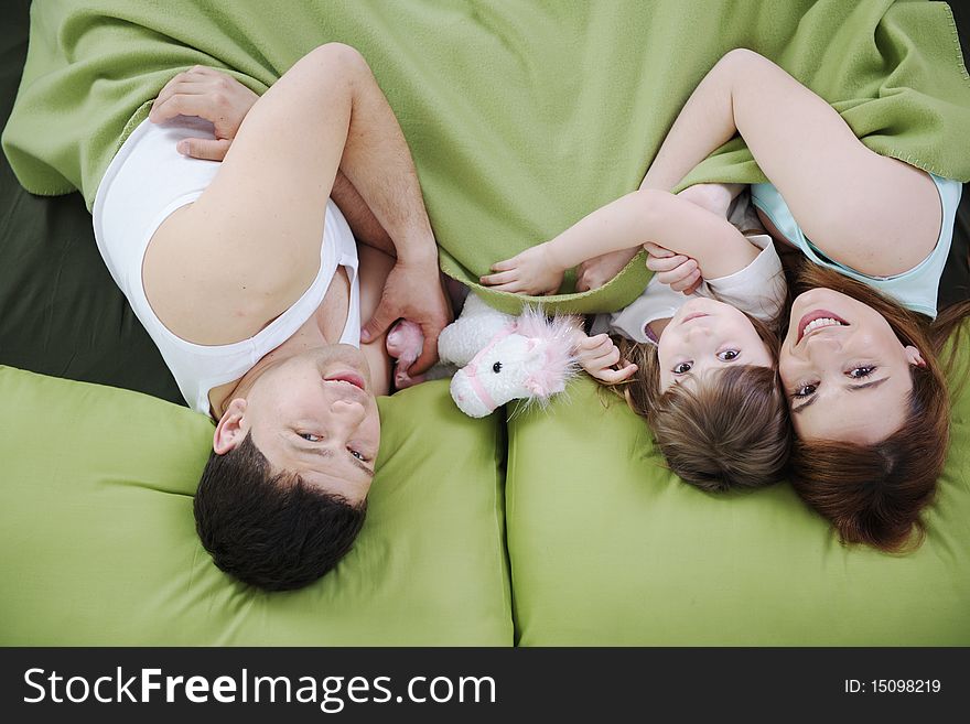 Happy young family at home relaxing in bed. Happy young family at home relaxing in bed