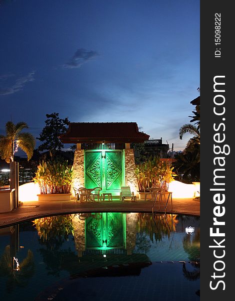 Relax corner in resort at udon thani in Thailand at night time, swimming pool and beautiful light. Background is big door which has thai art on the door.