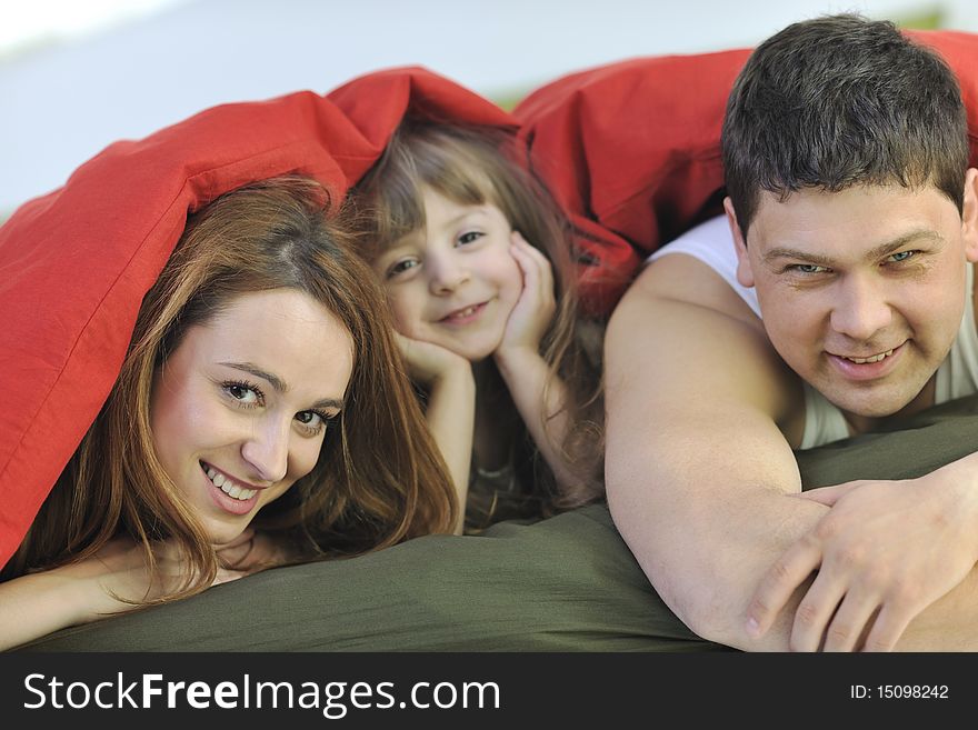 Happy young family at home relaxing in bed. Happy young family at home relaxing in bed