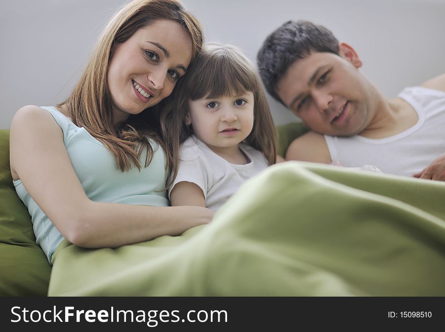 Happy young family at home relaxing in bed. Happy young family at home relaxing in bed