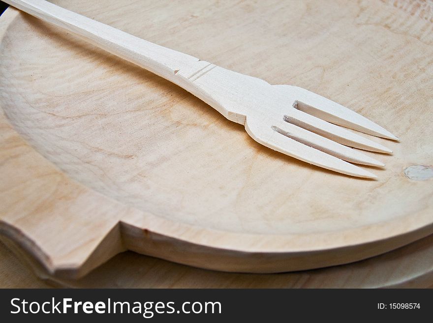 Detail of a wood fork arranged on a wood plate. Detail of a wood fork arranged on a wood plate