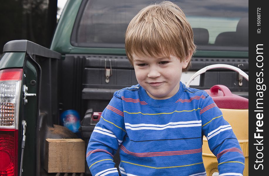 Young boy sitting on a truck bed and thinking. Young boy sitting on a truck bed and thinking.
