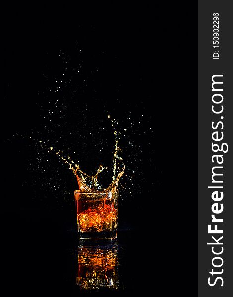 whiskey with splash on black background, brandy in a glass