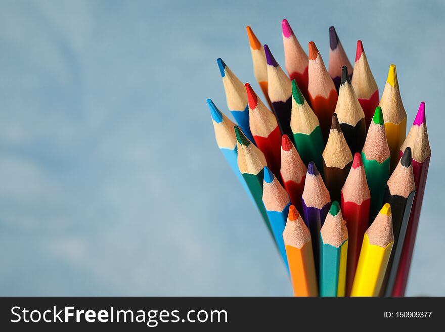 Multicolored pencils against light blue background