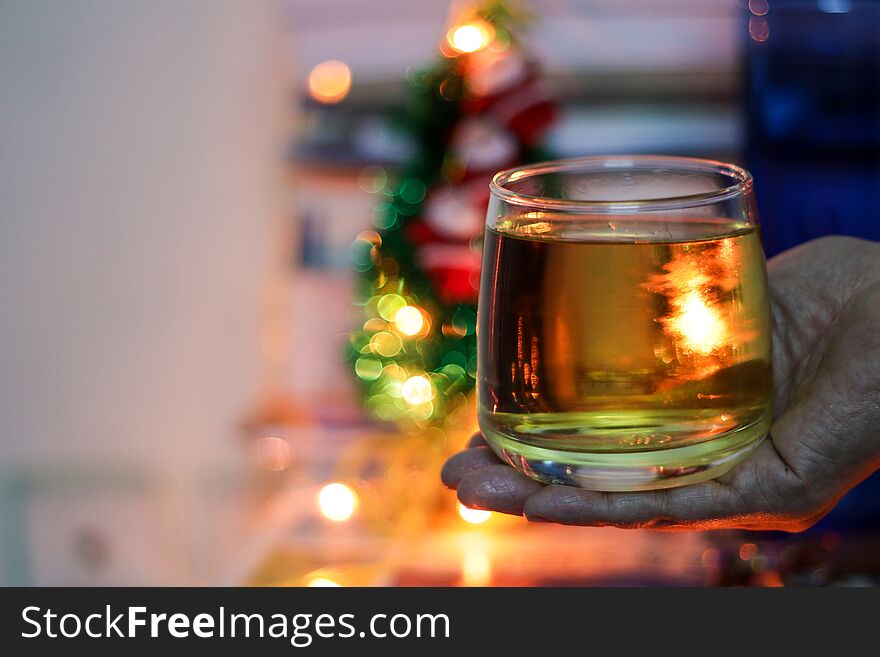 A glass of alcohol rum held in hand with background blurred bokeh lights
