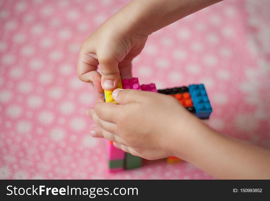 Small Hands Of The Child Collects The Bright Plastic Colored Designer. Educational Toys And Early Learning