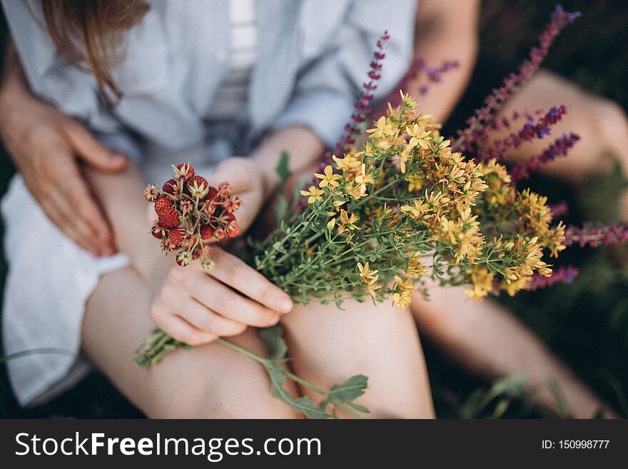 Hands And Legs Of Couple Holding Flowers And Berries