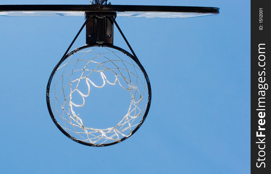 View of a basketball hoop from below, blue sky as a backdrop