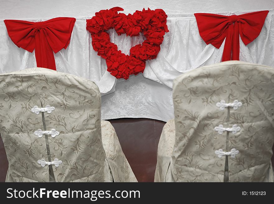 Two seats for wedding and red ribon heart with roses on table. Two seats for wedding and red ribon heart with roses on table.