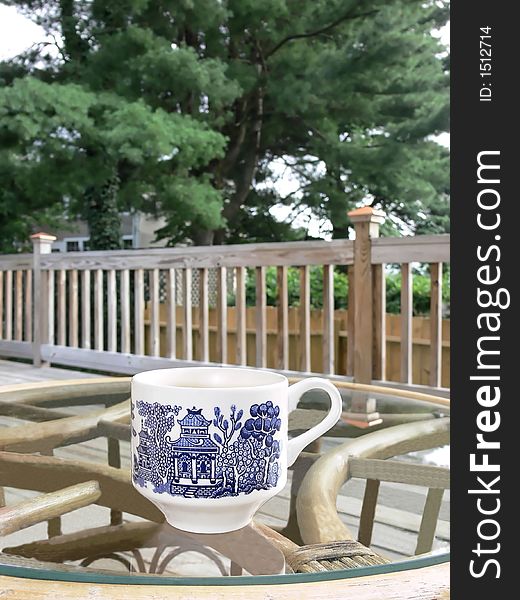 A coffee cup on a glass table on the porch.