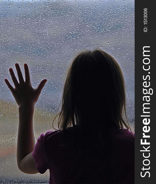 Little girl standing by window with raindrops on it on a rainy day. Little girl standing by window with raindrops on it on a rainy day