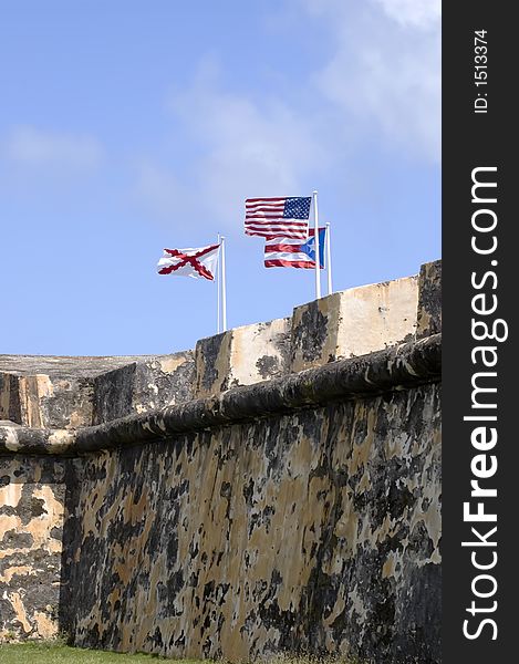 Cross of Burgundy, United States flag and Puerto Rican flag atop castle wall. Cross of Burgundy, United States flag and Puerto Rican flag atop castle wall