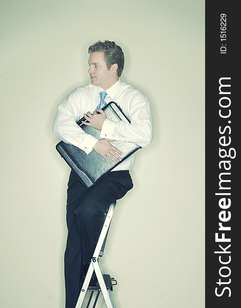 Businessman sits on top of a ladder holding his briefcase in his hands tightly. Businessman sits on top of a ladder holding his briefcase in his hands tightly
