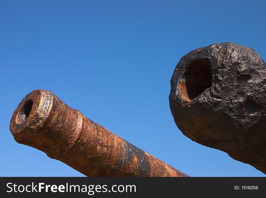 Two old cannon barrels against a clear blue sky. Two old cannon barrels against a clear blue sky