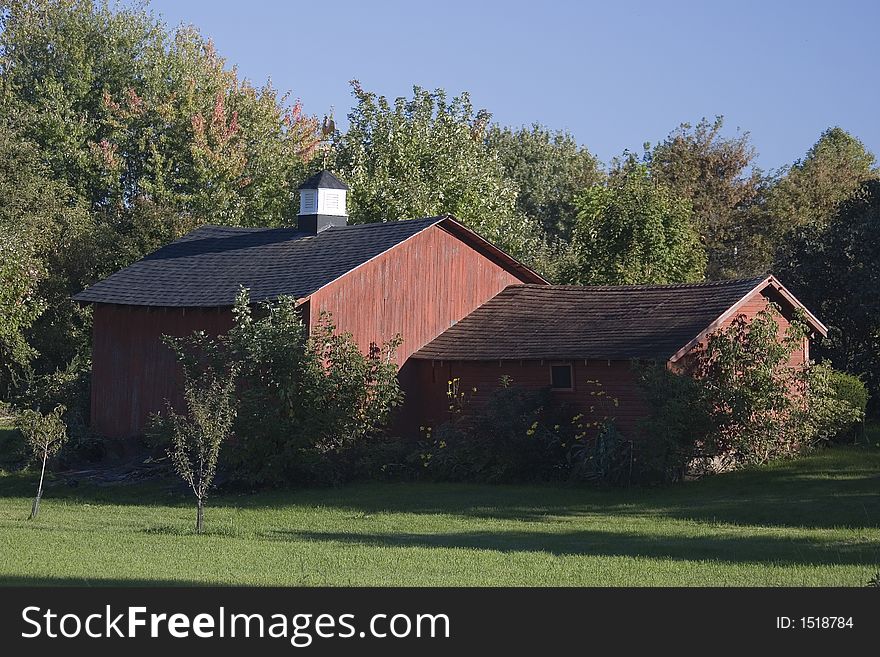 Photo of a red country barn on a bright summer day.