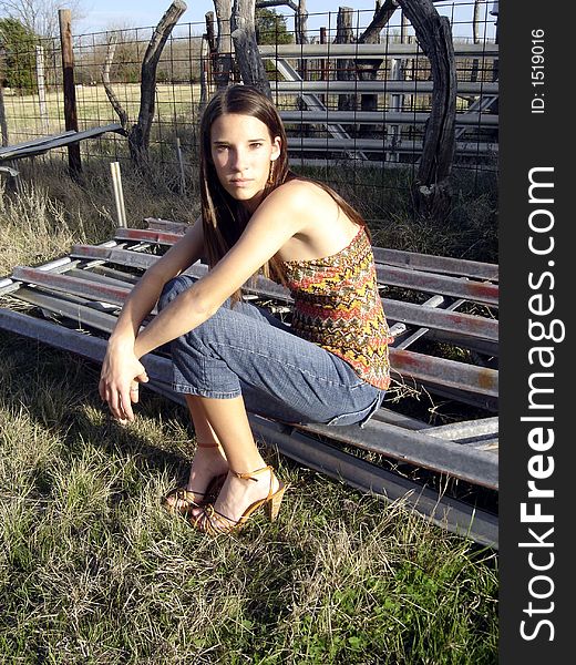 A pretty girl sitting on a gate with a rustic mood. A pretty girl sitting on a gate with a rustic mood.