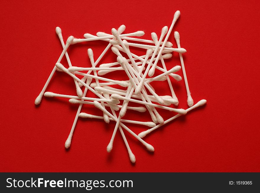 Pile of cotton buds on red background