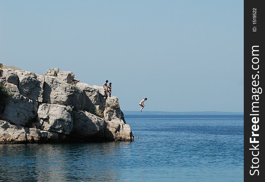 Girl jump from the stone in sea