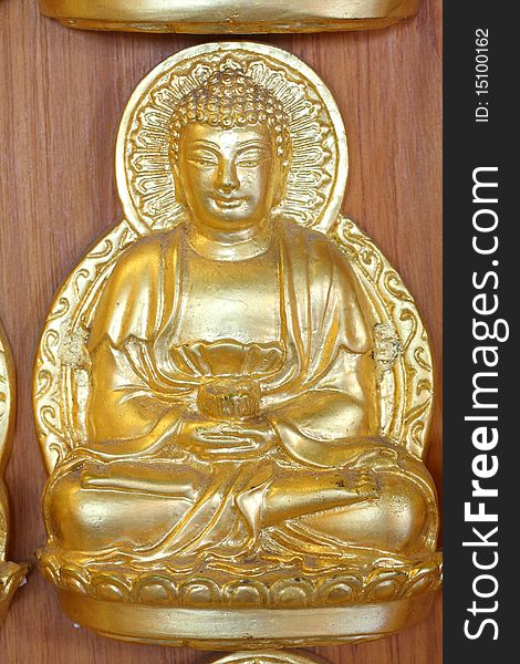 A gold buddha doll on the hard wood.