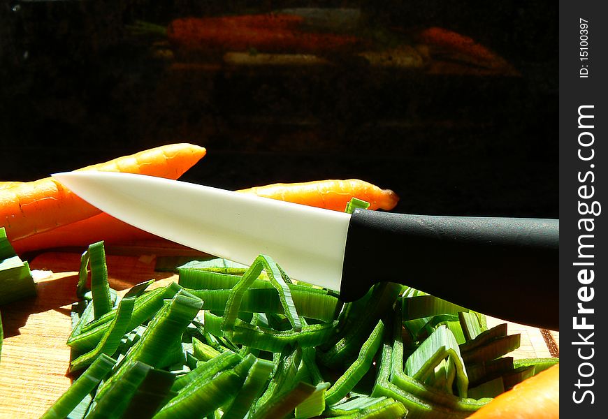 Scene with carrot, scallion and ceramic knife in the kitchen. Scene with carrot, scallion and ceramic knife in the kitchen