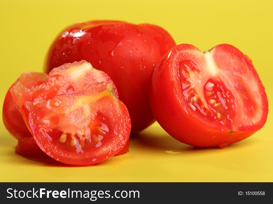 Fresh tomato (intact and sliced) with water drops on colored background. Fresh tomato (intact and sliced) with water drops on colored background