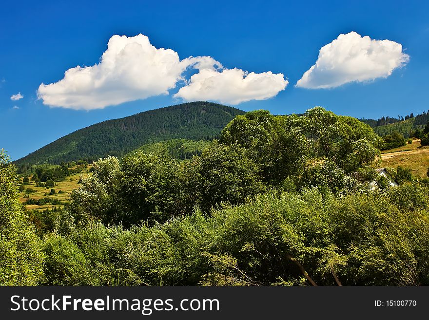 Blue sky view with white clouds over mountains with forest. Blue sky view with white clouds over mountains with forest.