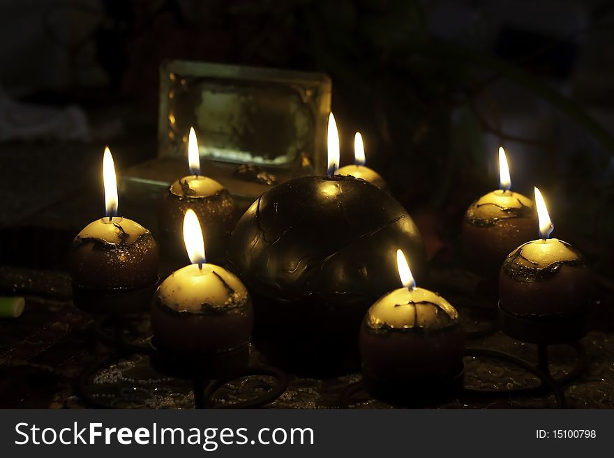 A collection of candles arranges around a bigger candle burning with soft light
