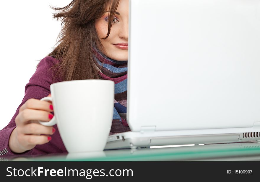 Young beautiful female sitting behind a laptop, holding a white cup. Young beautiful female sitting behind a laptop, holding a white cup