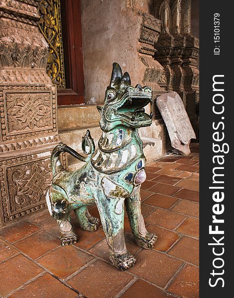 Statue of Singha or lion sitting on the front of gate way of temple in Laos